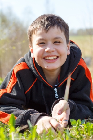close-up portrait of laughing  boy lying on the grassの写真素材
