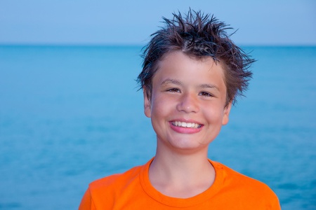 happy laughing boy of twelve in an orange T-shirt on the sea beachの写真素材