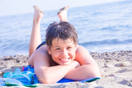 happy laughing boy of twelve with a scuba mask on the sea beachの写真素材