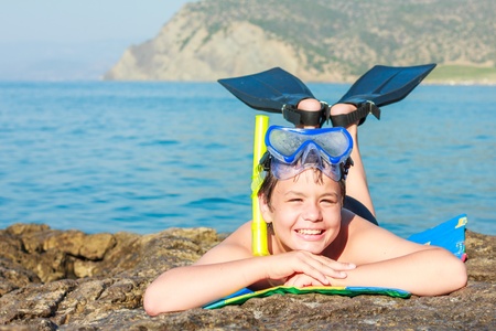 close-up portrait of a happy laughing boy of twelve in a mask and fins on the sea beachの写真素材