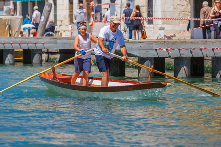 Venice, Veneto, Italy - May 24, 2015: Boy and man oarsmen, in boat race along the Cannaregio Canal in the Venice Vogalonga regatta. More than 1,500 boats take part in the annual historic regatta. Selective focus on the foregroundのeditorial素材