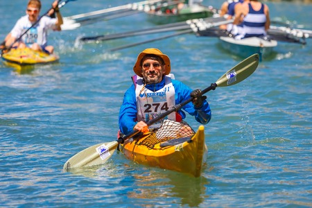 Venice, Veneto, Italy - May 24, 2015: Man oarsmen, in an orange boat race along the Cannaregio Canal in the Venice Vogalonga regatta. More than 1,500 boats take part in the annual historic regatta. Selective focus on the foregroundのeditorial素材