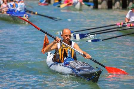 Venice, Veneto, Italy - May 24, 2015: Man oarsmen, in an orange boat race along the Cannaregio Canal in the Venice Vogalonga regatta. More than 1,500 boats take part in the annual historic regatta. Selective focus on the foregroundのeditorial素材