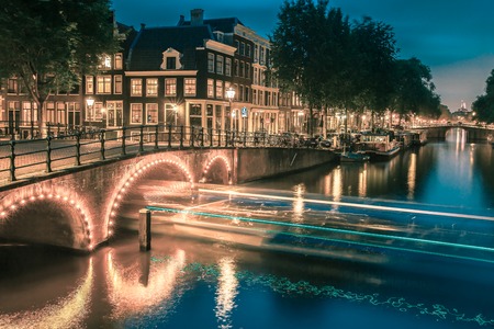 Night city view of Amsterdam canal, bridge and typical houses, boats and bicycles, Holland, Netherlands.. Toning in cool tonesの写真素材