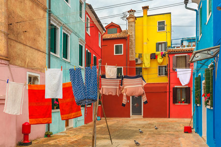 Patio with colorful houses with laundry drying on a rope on the famous island Burano, Venice, Italyの写真素材