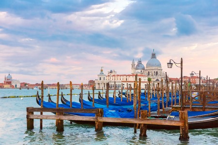 Mooring for gondolas on Piazza San Marco at sunset in Venice, Basilica of Saint Mary of Health or Basilica di Santa Maria della Salute on the background, Italyの写真素材