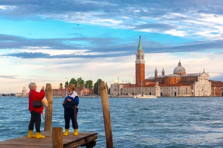 Venice, Italy - May 23, 2015: Tourists take pictures of each other in the background Gondolas moored by Saint Mark square and San Giorgio di Maggiore island at twilightのeditorial素材
