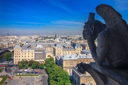 The Stryge (most famous of the Chimeres) looking toward the Eiffel Tower and the district of La Defense at Notre Dame Cathedral in Parisの写真素材