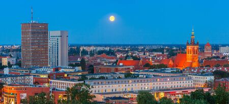 Aerial panorama of modern city and Old Town with Church of Saint Catherine at moonlight night in Gdansk, Polandの写真素材