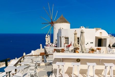 Picturesque view of windmill, empty restaurant and white houses in Oia or Ia on the island Santorini, Greeceの写真素材