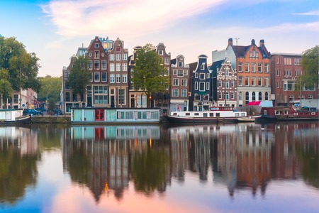 Amsterdam canal Amstel with typical dutch houses and boats during sunrise, Holland, Netherlands.の写真素材