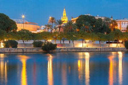 Quay of the river Guadalquivir, Famous Bell Tower named Giralda and Maestranza during evening blue hour, Seville, Andalusia, Spainの写真素材