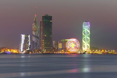 View from Sea Beach to Illuminated cityscape with Skyscrapers, ferris wheel and Alphabet Tower at night, Batumi, Adjara, Georgiaの写真素材