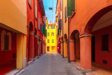 Medieval street portico with bright colored houses in the Old Town in the sunny day, Emilia-Romagna, Italyの写真素材