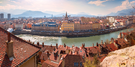 Scenic panoramic aerial view of the banks of the Isere river, bridge, and Old Town with French Alps on the background, Grenoble, Franceの写真素材