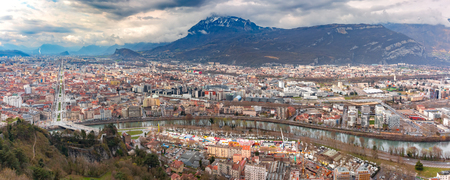 Scenic panoramic aerial view of the banks of the Isere river, bridge, roofs and French Alps on the background, Grenoble, Franceの写真素材