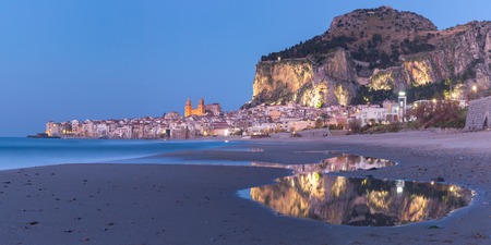 Beautiful panoramic view of the beach and old town of coastal city Cefalu during evening blue hour, Sicily, Italyの写真素材
