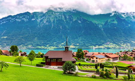 Panoramic view of swiss village Iseltwald with traditional wood church on the southern shore of Lake...