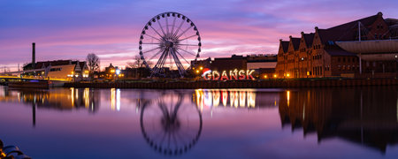 Panorama of Motlawa River and Ferris wheel with water reflection in Old Town of Gdansk at night,...