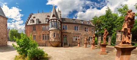 Panorama of stone statues in a historic courtyard with a turreted building in Marburg, Germanyの写真素材