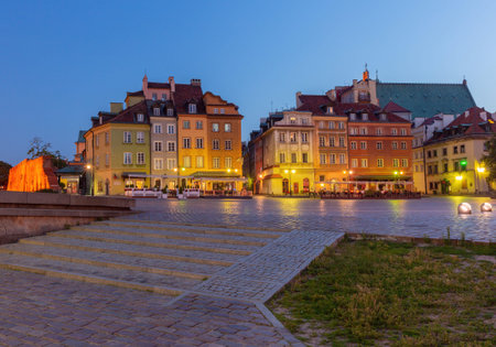 Early morning view of the colorful historic buildings in Warsaws Old Town Square, Poland, with illuminated facades and cobblestone streets, highlighting the architectural charm at dawnの写真素材