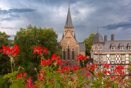 St. Johannis Church with its Gothic-style spire and stone facade, surrounded by trees and historic half-timbered houses in Wernigerode, Germanyの写真素材
