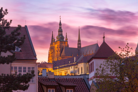View of St Vitus Cathedral above rooftops at sunset in Prague, Czech Republicの写真素材