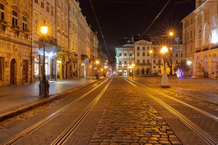 Night view of Rynok Square with historic buildings and tram tracks in Lviv Ukraineの写真素材