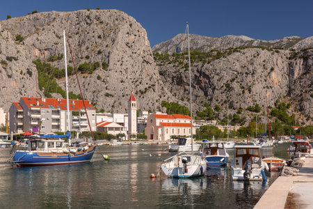 Boats moored in the harbor with mountains in the background in Omis Croatiaの写真素材