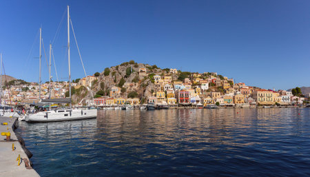 Panoramic waterfront view of Symi harbor in Greece with yachts and colorful hillside houses