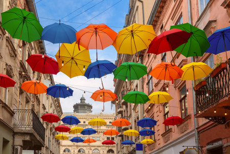 Floating colorful umbrellas suspended above a street in Lviv, Ukraine, with historical buildings in the backgroundの写真素材