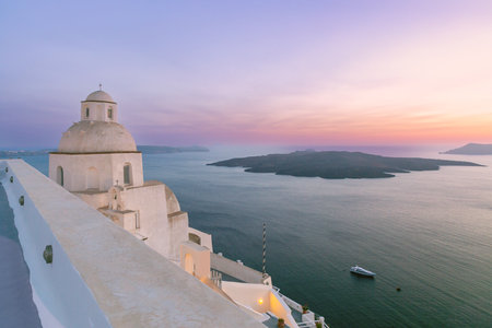 Church dome and Aegean Sea caldera at sunset in Fira on the island of Santorini, Greeceの写真素材