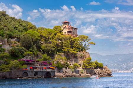 Seaside villa on rocky cliff surrounded by trees in Portofino, Italy, Liguria regionの写真素材