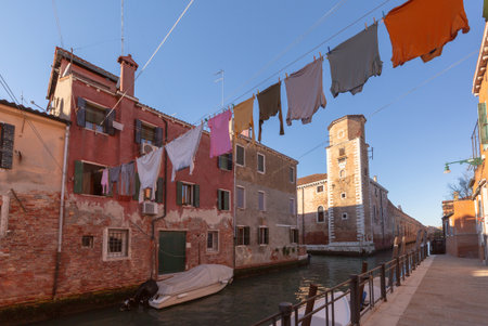 Colorful houses with hanging laundry and old brick tower along canal in Venice, Italyの写真素材