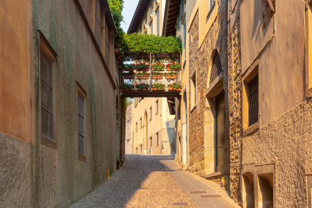 Cobblestone alley with floral bridge and historic buildings in Bergamo, Lombardy, Italyの写真素材
