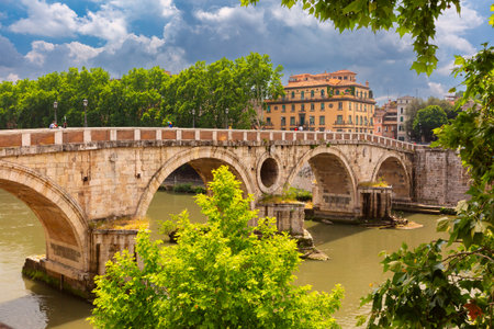 Historic Ponte Sisto bridge crossing the Tiber River with trees and buildings in Rome, Italyの写真素材