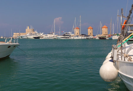 View of yachts, medieval windmills and Fort Saint Nicholas at Mandraki harbor in Rhodes, Greeceの写真素材