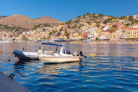 Scenic harbor of Symi island in Greece with colorful waterfront houses and boats on calm...