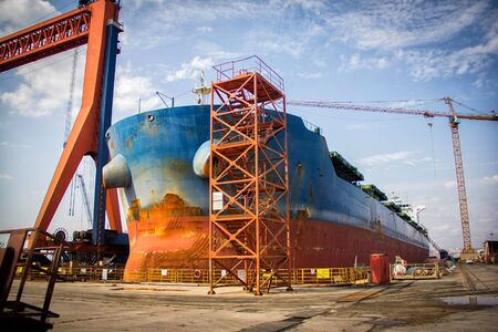 A large tanker cargo ship is being renovated and painted in shipyard dry dockの写真素材