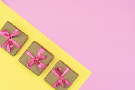 flat-lay of Gift present boxes with pink ribbon on pink and yellow background. Gift spring concept....