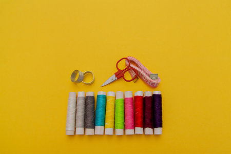 Thread, needles, scissors and meter on yellow background. tailoring set. sewing kit multi-colored.