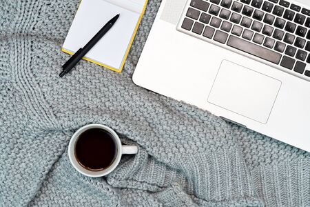 Flatlay of Cosy working writing place with warm sweater coffee, laptop and writing accesories. work from home. Writing. Warm concept in cold weather.の写真素材