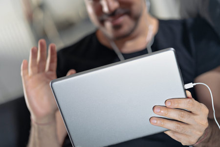 man holding using digital tablet and headphones sitting on a sofa. Online education, working, video...