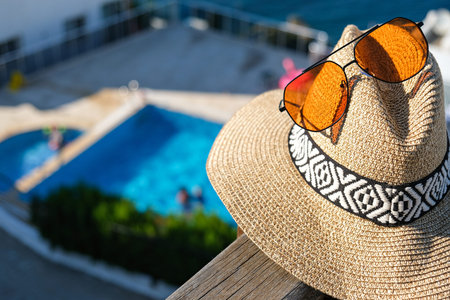 straw hat with sunglasses wooden terrace of holiday villa or hotel with sea and wimming pool view