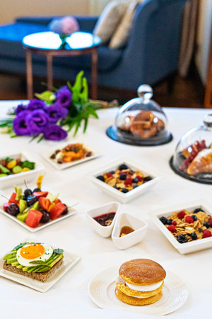 Tray plates with assorted breakfast meal on a bed in a hotel room