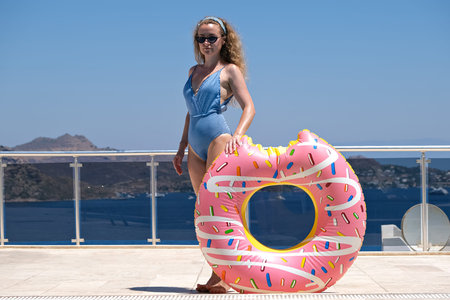 Beautiful women in sunglasses posing with inflatable donut near swimming pool at resort