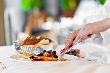 woman eating breakfast in the bed in hotel. Fresh croissant bread fruits in plate.の写真素材