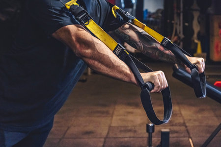Man Does Crossfit exercise With Trx Fitness Straps In Gym
