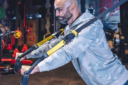 Man Does Crossfit exercise With Trx Fitness Straps In Gym