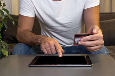 online shopping man paying order online with tablet and credit card from home